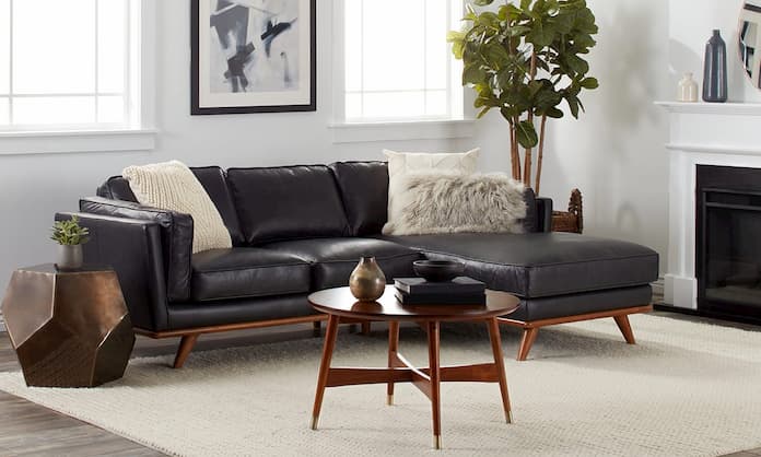 modern black leather sofa with wooden coffee table plants and side table
