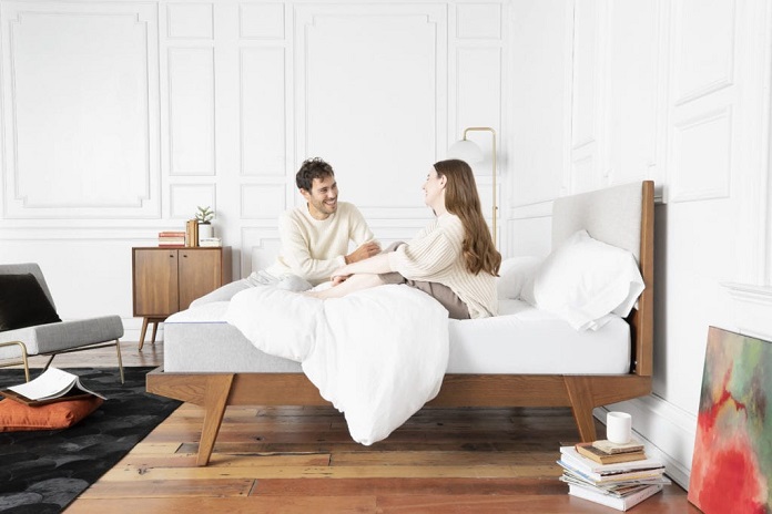 couple sitting on bed with a new mattress