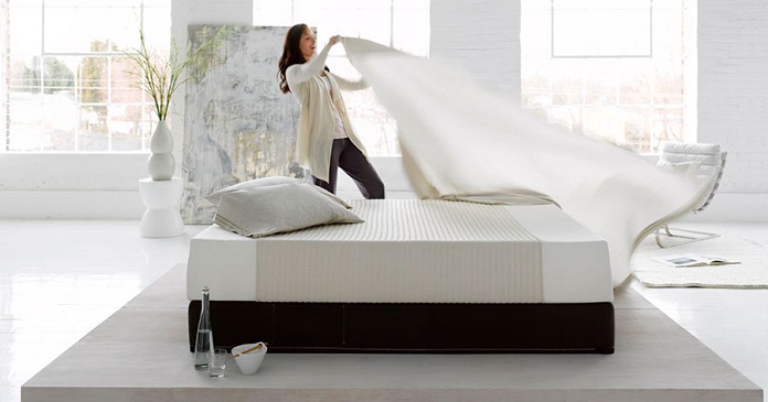 woman placing bed sheets on mattress