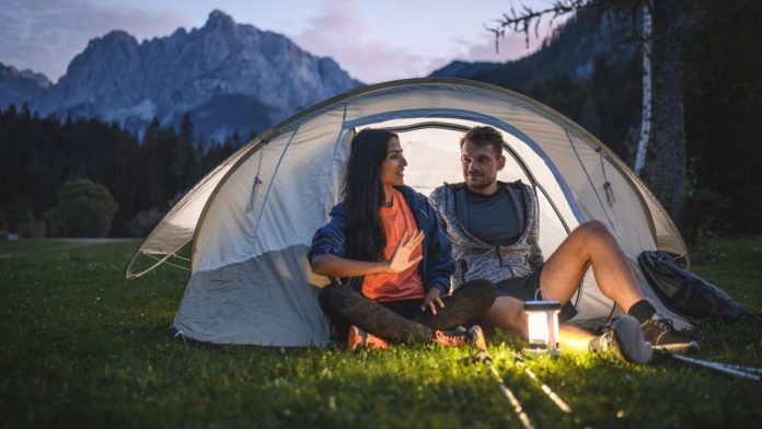 Couple sitting at night in 2 man tent with a led light