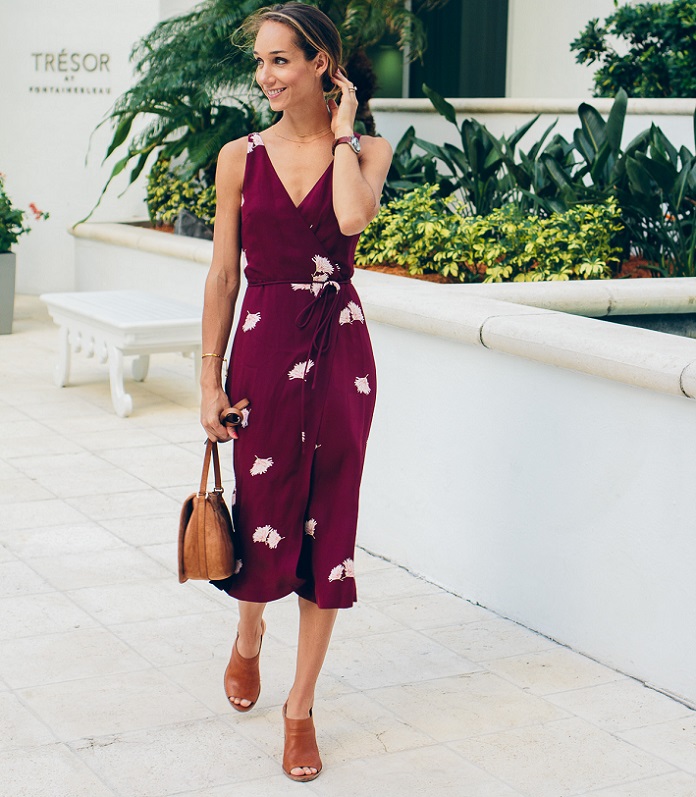 picture of a woman walking by a greenery wearing wrap dress 
