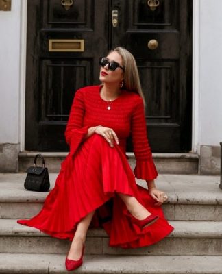 picture of a woman in red dress sitting on stairs in front a building door