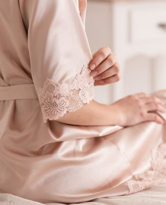 woman sitting on a bed while wearing a lingerie robe