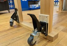 Close-up view of a wooden cart's locking caster wheels on a hardwood floor, providing stability and ease of movement for utility furniture.